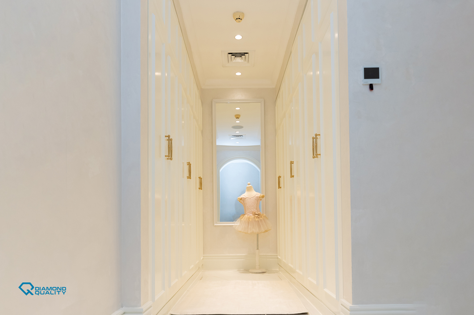 Bright hallway with white built-in wardrobes and gold handles in modern villa renovation Dubai.